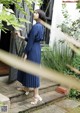 A woman standing in front of a door wearing a blue dress.