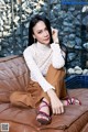 A woman sitting on top of a brown couch.