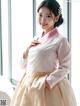 A woman in a pink and white hanbok posing for a picture.