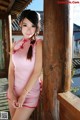 A woman in a pink dress posing for a picture.