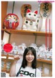 A woman standing in front of a shelf filled with cat figurines.