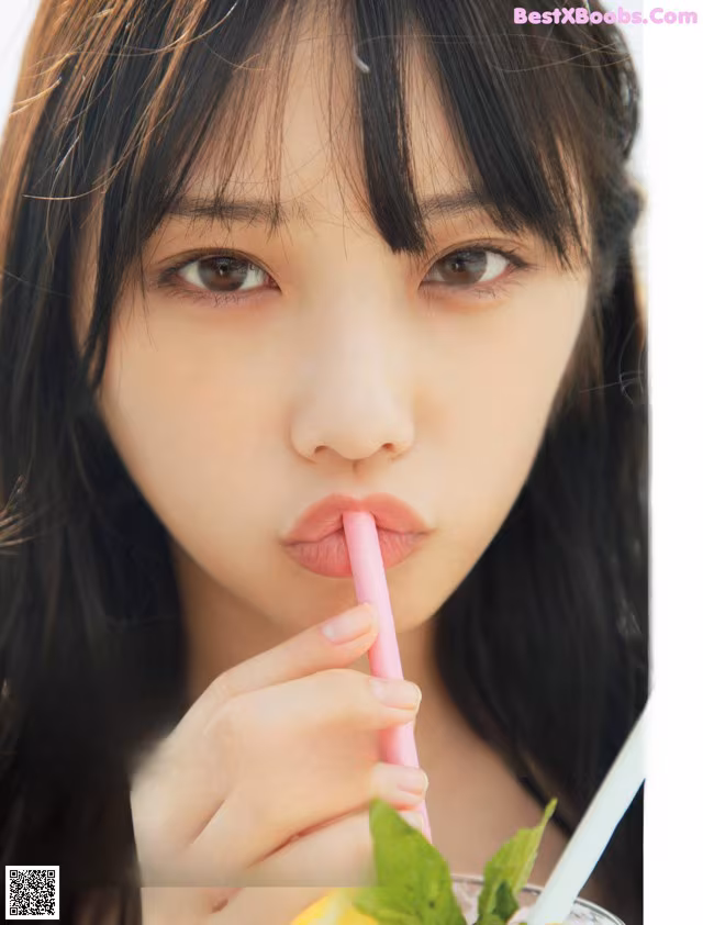A young woman holding a straw in her mouth.