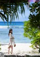 A woman in a white dress standing on a beach.