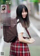 A young woman in a school uniform with a backpack.