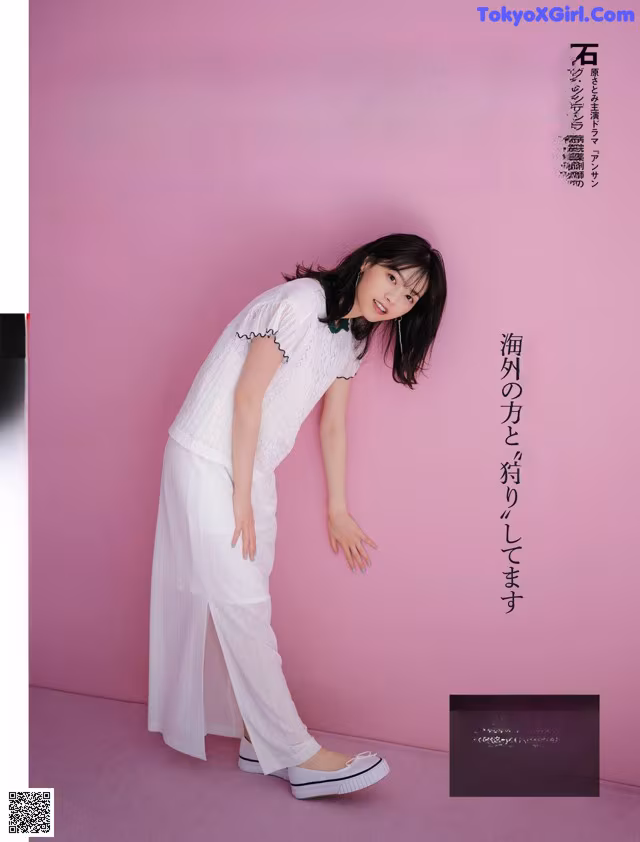 A woman in a white shirt and white pants posing for a magazine.