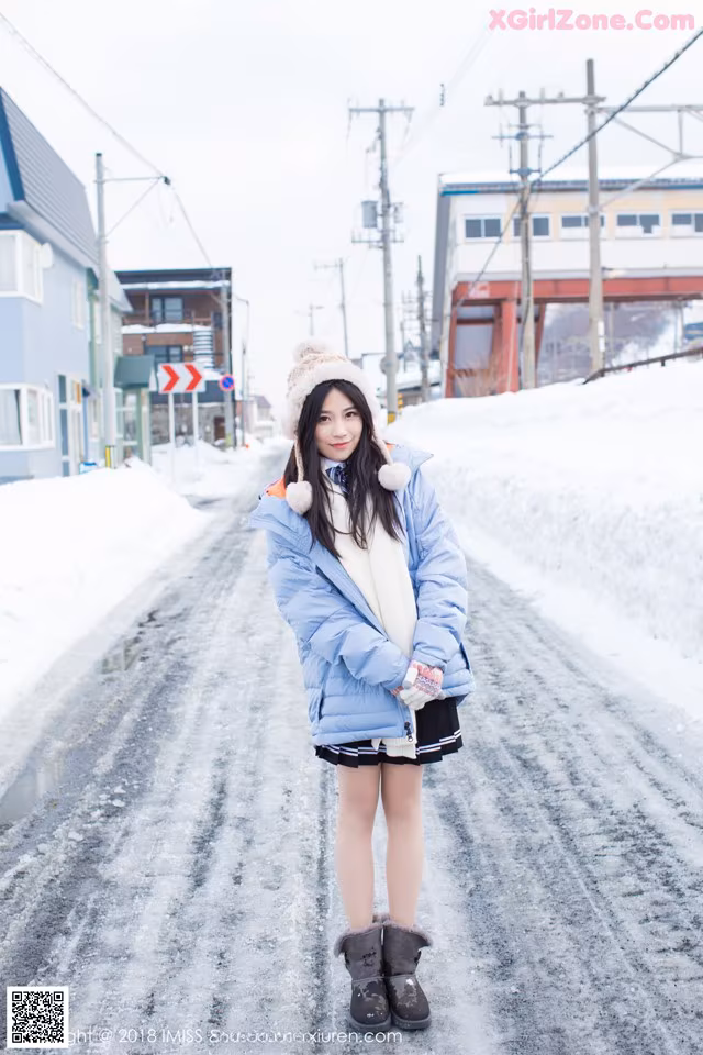 A woman standing in the middle of a snow covered road.