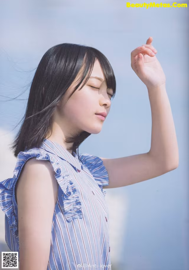 A woman in a blue and white striped shirt is posing for a magazine.