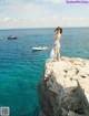 A woman standing on top of a cliff overlooking the ocean.