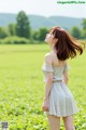 A woman standing in a field of green grass.