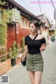 A woman in a black top and green skirt walking down a street.