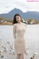 a woman in a beige dress standing on a beach