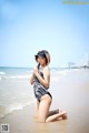 A woman in a bathing suit and hat on the beach.