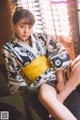 A woman in a kimono sitting on a window sill.